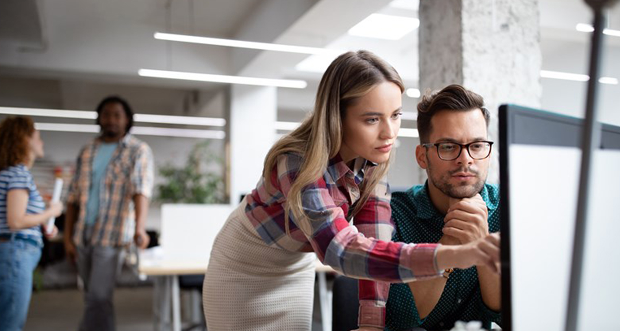 A lady pointing at a computer screen with a man next to her