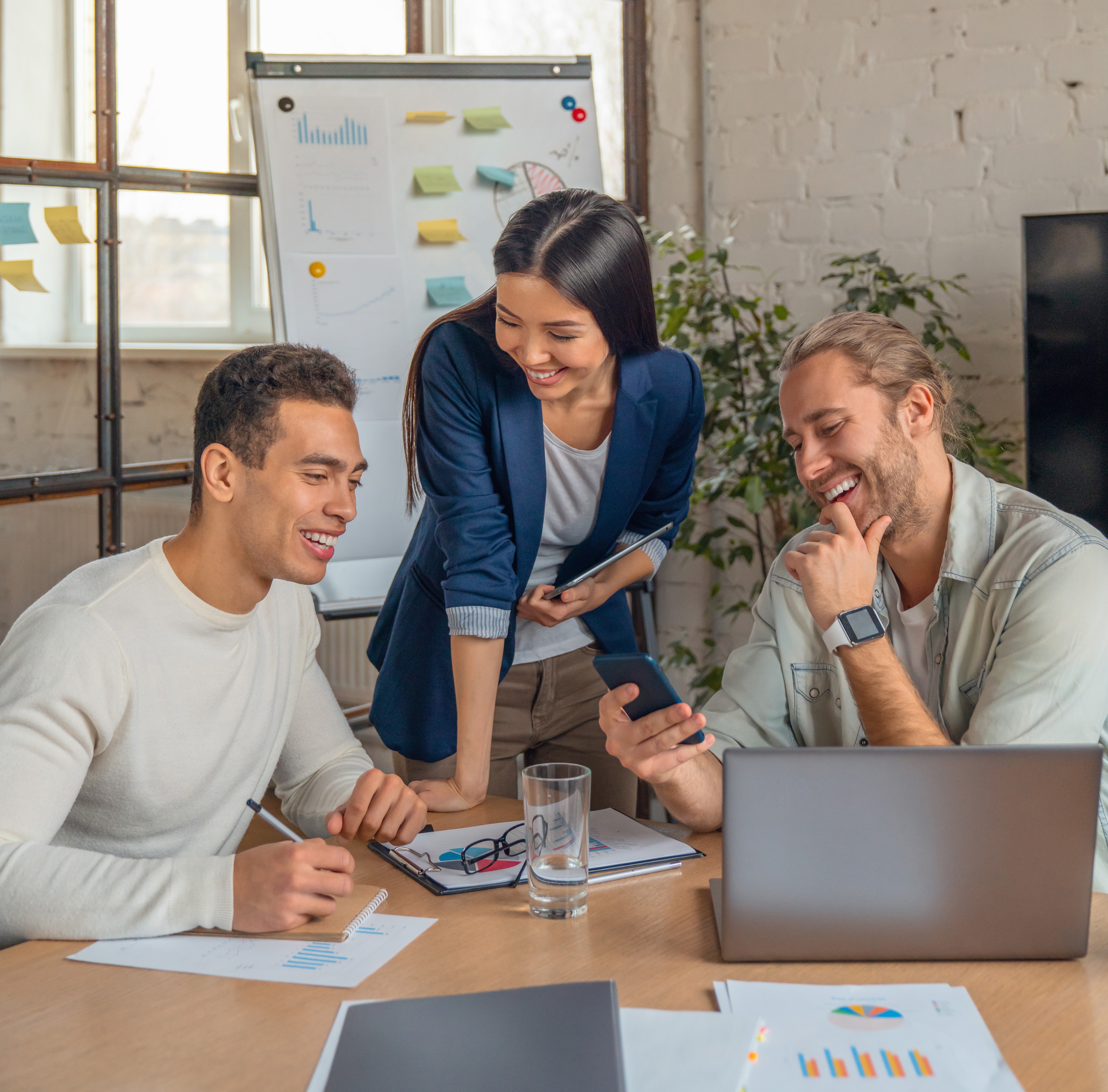 2 males and 1 female smiling during a meeting with a laptop in front of them